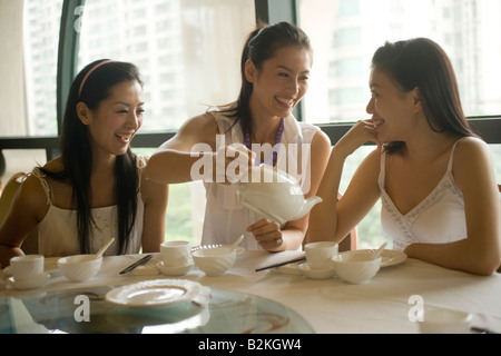 Jeune femme servir le thé à ses amis dans un restaurant and smiling Banque D'Images