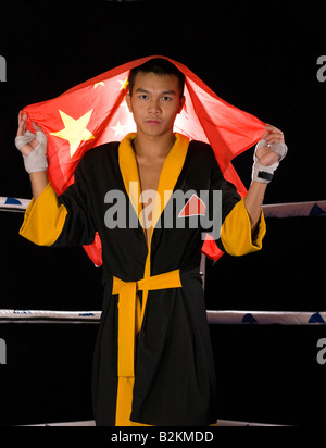 Jeune homme tenant un drapeau chinois dans un ring de boxe Banque D'Images