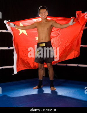 Jeune homme tenant un drapeau chinois dans un ring de boxe Banque D'Images