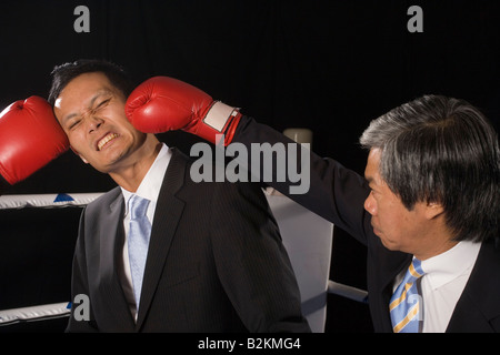 Homme d'affaires d'être atteint par ses deux adversaires dans un ring de boxe Banque D'Images