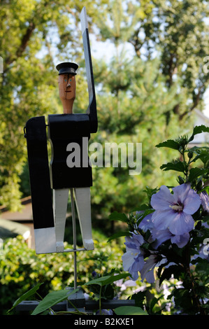 Un agent de la circulation whirly-man ornement jardin flanqué de Rose de Sharon et en proie à la gloire du matin Banque D'Images