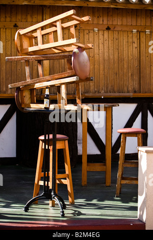 Tabourets en bois empilées l'une sur l'autre devant un bar fermé à Cala Ratjada, Majorque, Espagne Banque D'Images