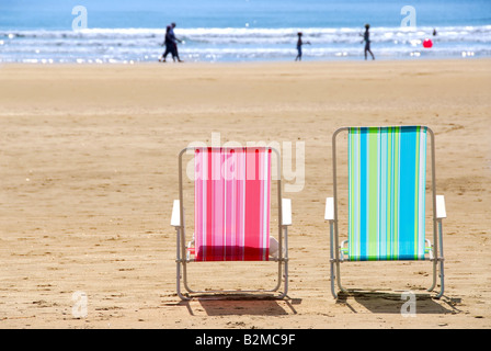 Deux chaises de plage coloré vide sur une plage de sable fin Banque D'Images
