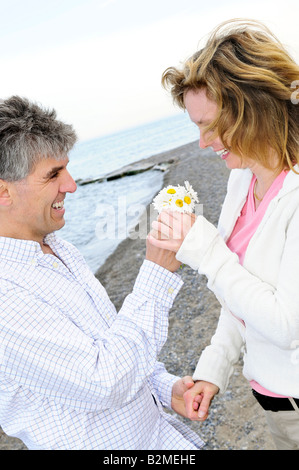 D'âge mûr jouissant d'un moment romantique avec des fleurs Banque D'Images
