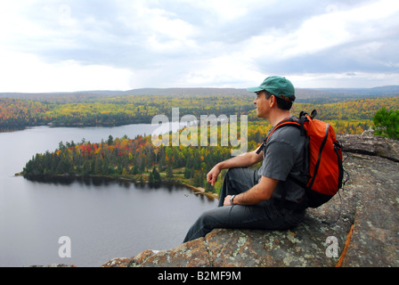 Un randonneur assis sur une falaise, bénéficiant d'une vue panoramique Banque D'Images