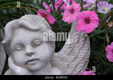 Les pétunias roses poussent sur une statue d'un chérubin dans un jardin à Mount Pleasant SC Banque D'Images