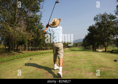 Vue arrière d'un homme mûr se balancer un club de golf dans un terrain de golf Banque D'Images
