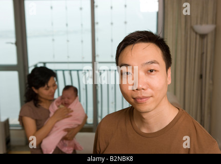 Portrait of a Mid adult man holding sa femme avec sa fille dans l'arrière-plan Banque D'Images