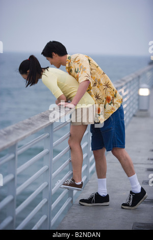 Portrait of a young couple leaning et regardant en bas, Huntington Beach, Californie, USA Banque D'Images