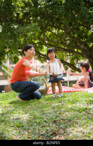 Mid adult woman et ses filles jouant avec disque en plastique dans un parc, à Singapour Banque D'Images