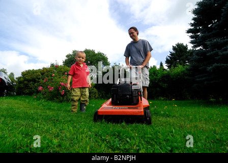 Avec son père alors que tondre la pelouse du jardin de l'herbe verte Banque D'Images