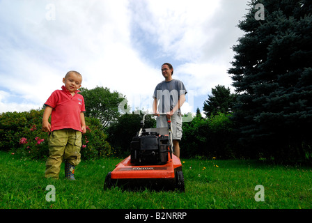 Avec son père alors que tondre la pelouse du jardin de l'herbe verte Banque D'Images