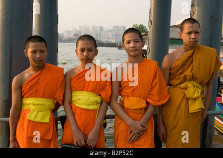 Quatre moines novices garçon thaïlandais s'aligner face à l'appareil photo en attente d'une rivière taxi Bangkok Thaïlande Banque D'Images