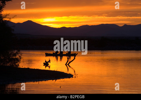 Les pêcheurs tentent leur chance à partir de bateaux sur les eaux d'or d'un lac miroitant au coucher du soleil après une belle journée d'été au Colorado Banque D'Images