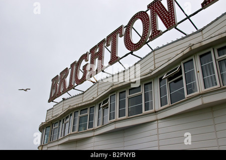 Une mouette voler au-delà d'un signe sur la jetée de Brighton à West Sussex. Banque D'Images