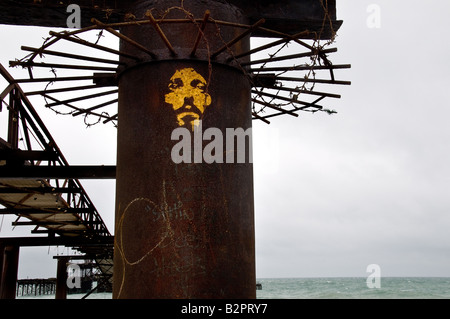 Un visage pulvérisé sur une colonne de support restant de l'ancienne jetée de Brighton à West Sussex. Banque D'Images