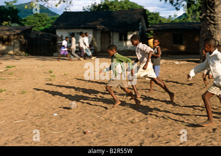 Garçons jouant au football avec un ballon à la main au Malawi. Banque D'Images