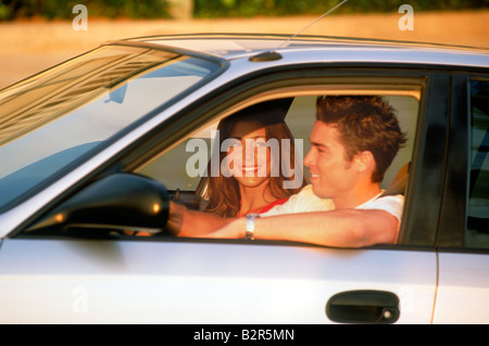 Bénéficiant d'un couple de jeunes adultes en voiture aux États-Unis dans la lumière au coucher du soleil Banque D'Images