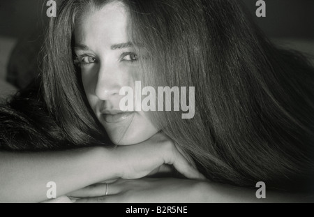 Très jolie adolescente aux cheveux longs portant sur bed looking at camera Banque D'Images