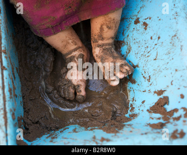 Les pieds des enfants jouant dans le sable humide pit Banque D'Images