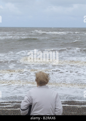 Vieille Femme debout par plage de Muro, au nord du Pays de Galles Banque D'Images