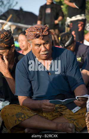 La plage de Kuta à Bali Indonésie personnes homme femme groupe chanter la joie la tristesse la mort la vie célébration hindoue cérémonie de crémation priant Banque D'Images