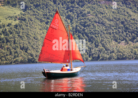 Couple de retraités de la voile d'un bateau à voile vert avec red sails sur Ullswater, le Parc National du Lake District, Cumbria, Angleterre. Banque D'Images