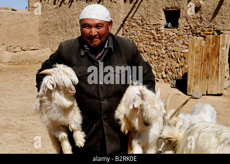Portrait d'un homme tenant deux jeunes chèvres velues dans ses mains Banque D'Images