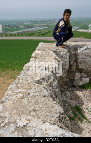 Garçon syrien sur la muraille romaine dans les ruines d'Apamée de Syrie Banque D'Images