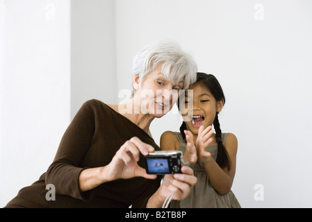 Senior woman growing et petite-fille avec un appareil photo numérique, les deux rient Banque D'Images