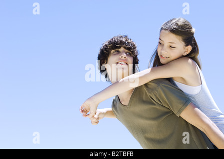 Teen boy carrying jeune sœur sur le dos, les deux, low angle view Banque D'Images