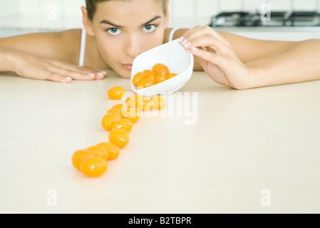 Tomates cerises jaunes déversant femme sur un petit plat, looking at camera Banque D'Images