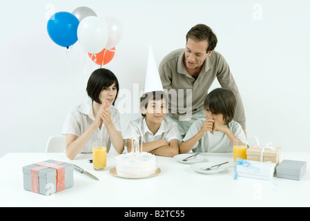 Le garçon d'anniversaire avec la famille, looking at camera Banque D'Images