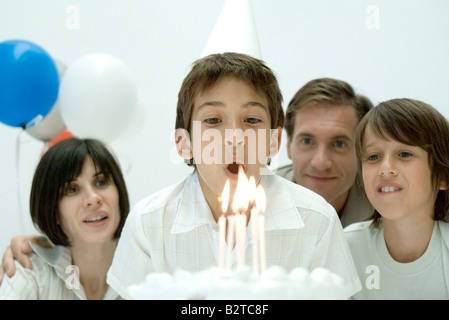Garçon sur le point de souffler les bougies sur le gâteau d'anniversaire, l'observation de la famille Banque D'Images