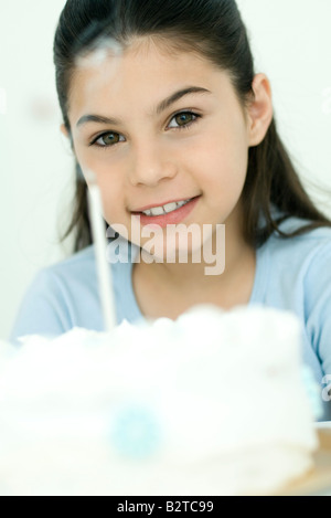 Girl smiling at camera après soufflant sur les bougies du gâteau d'anniversaire, portrait Banque D'Images