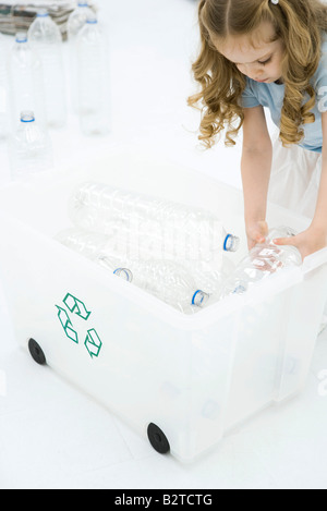 Petite fille se pencher, placer les bouteilles en plastique dans le bac de recyclage Banque D'Images