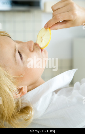 Woman eating tranche de citron, tête en arrière, cropped view Banque D'Images