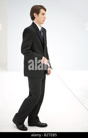 Businessman walking avec canne blanche, side view Banque D'Images