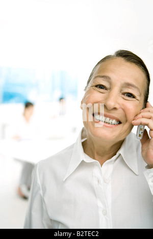 Senior woman using cell phone, smiling at camera Banque D'Images