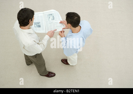 Deux hommes à la recherche à l'ensemble de journaux, overhead view Banque D'Images