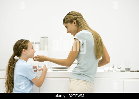 Mère et fille dans la cuisine, la femme tenant le menton de la jeune fille, smiling Banque D'Images