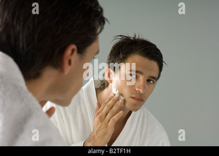 L'homme en se regardant dans le miroir, l'application de la crème à raser Banque D'Images