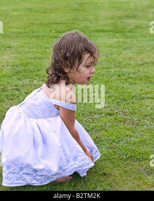 Petite fille à genoux dans le parc Banque D'Images