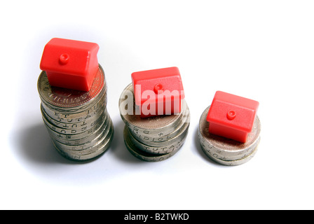 Petit rouge maisons modèles empilés sur des piles de pièces de la propriété des objets isolés du marché du logement de l'échelle des concepts par le resserrement du crédit Banque D'Images