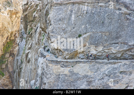 Les randonneurs sur un chemin précaire dans les montagnes au-dessus de la vallée de l'Hunza Karimabad dans le Nord du Pakistan Banque D'Images