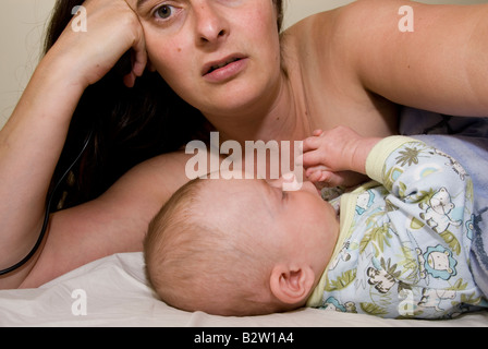 Bébé Garçon Joshua Kailas âgés de 15 semaines Hudson suceurs et les doigts dans le lit avec assez de Mère Deborah Waters Banque D'Images