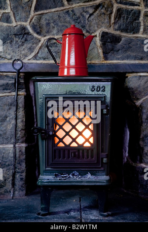 Électrique rouge se trouve au-dessus d'un poêle à bois traditionnel Banque D'Images