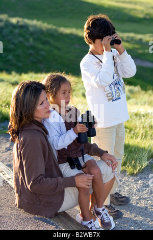 Hispanic family l'observation de la faune avec les jumelles dans le Parc National de Yellowstone au Wyoming Banque D'Images