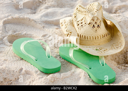 Des tongs et un chapeau de soleil sur une plage Banque D'Images