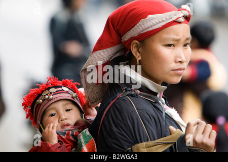 Femme Dzao rouge avec bébé sur le dos en écharpe Vietnam Sapa hilltribe Banque D'Images